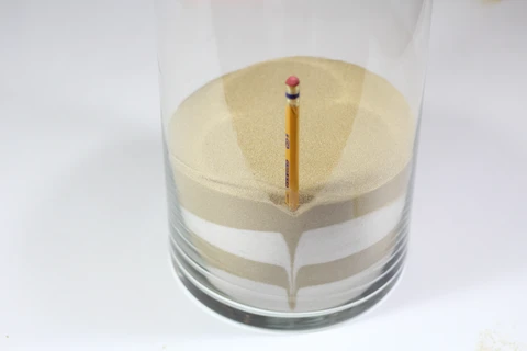 Use a pencil to push the sand down around the edge of the vase in order to create patterns.